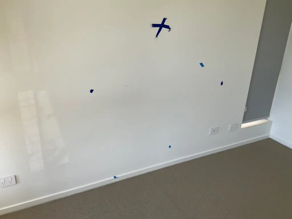 Building inspector checking painted walls for qualify of finish during practical completion inspection in Sydney home.